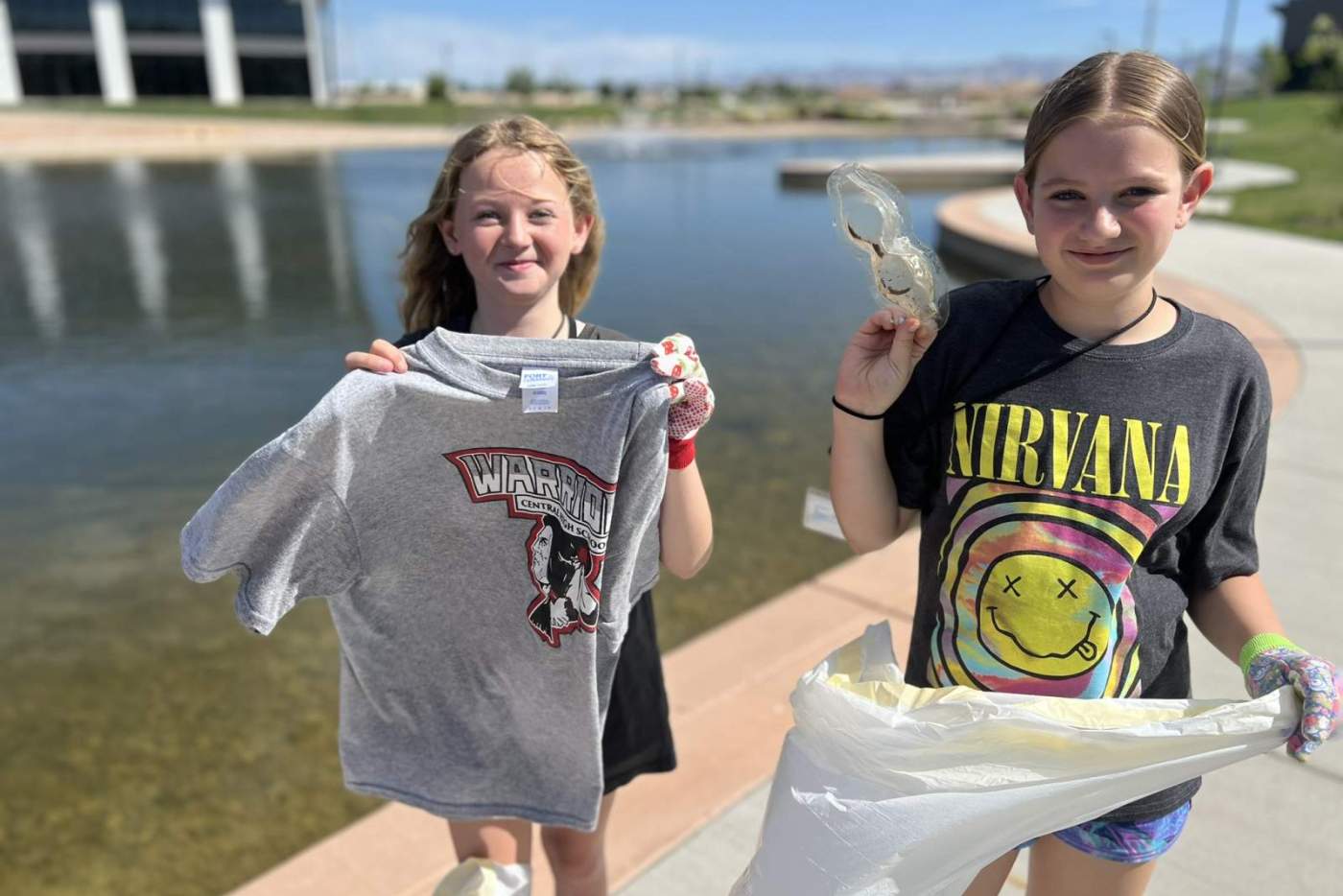 2 girls hold trash they collected