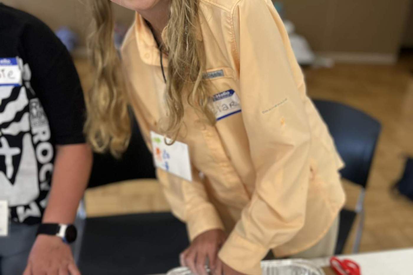 Girl in peach shirt with metal tray holing clay dam model