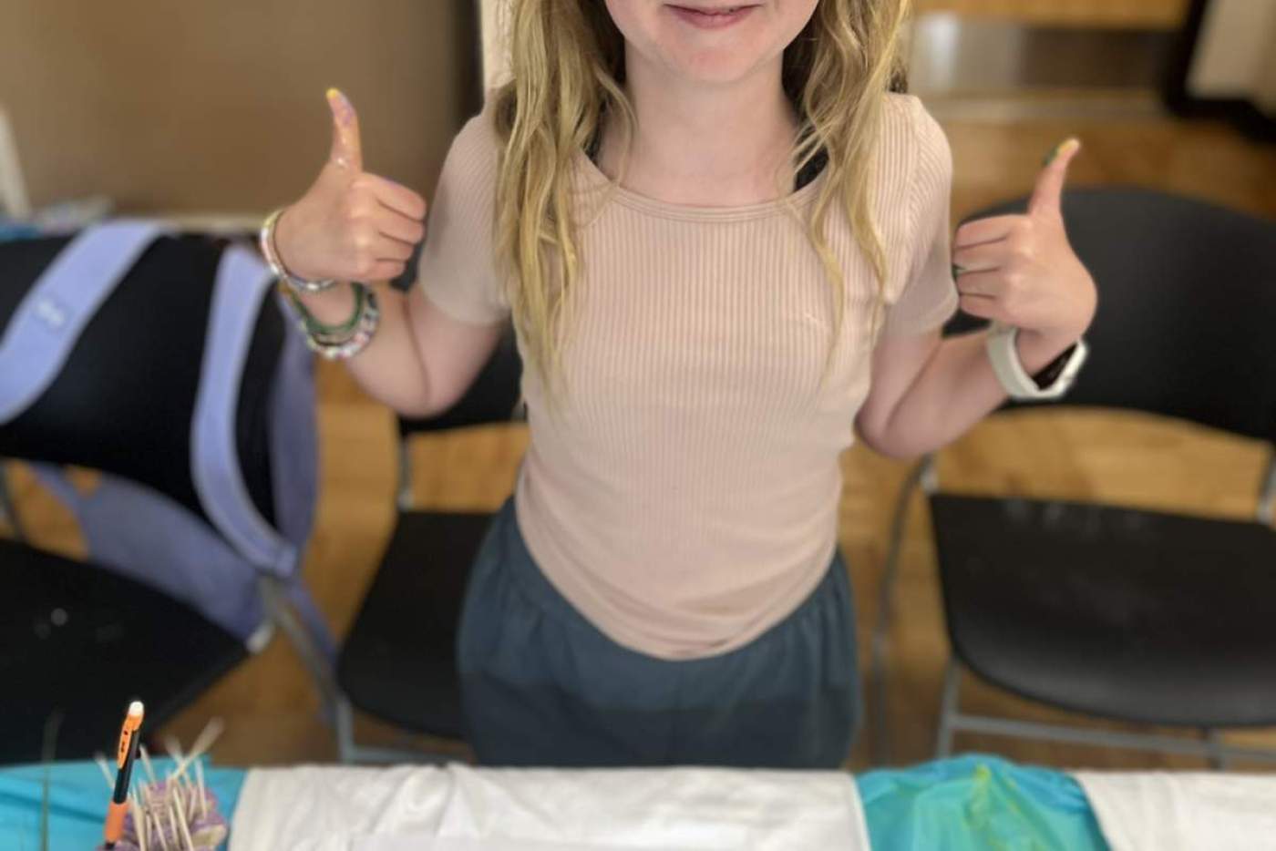 girls gives two thumbs up, standing over t-shirt she designs