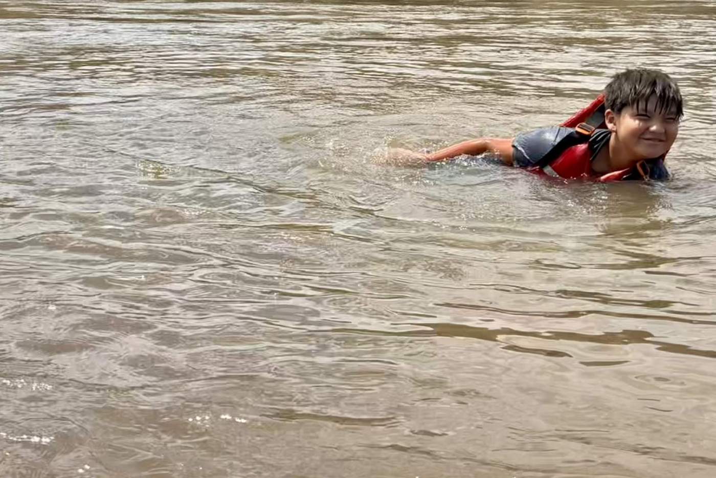 Boy in life vest swimming in a river