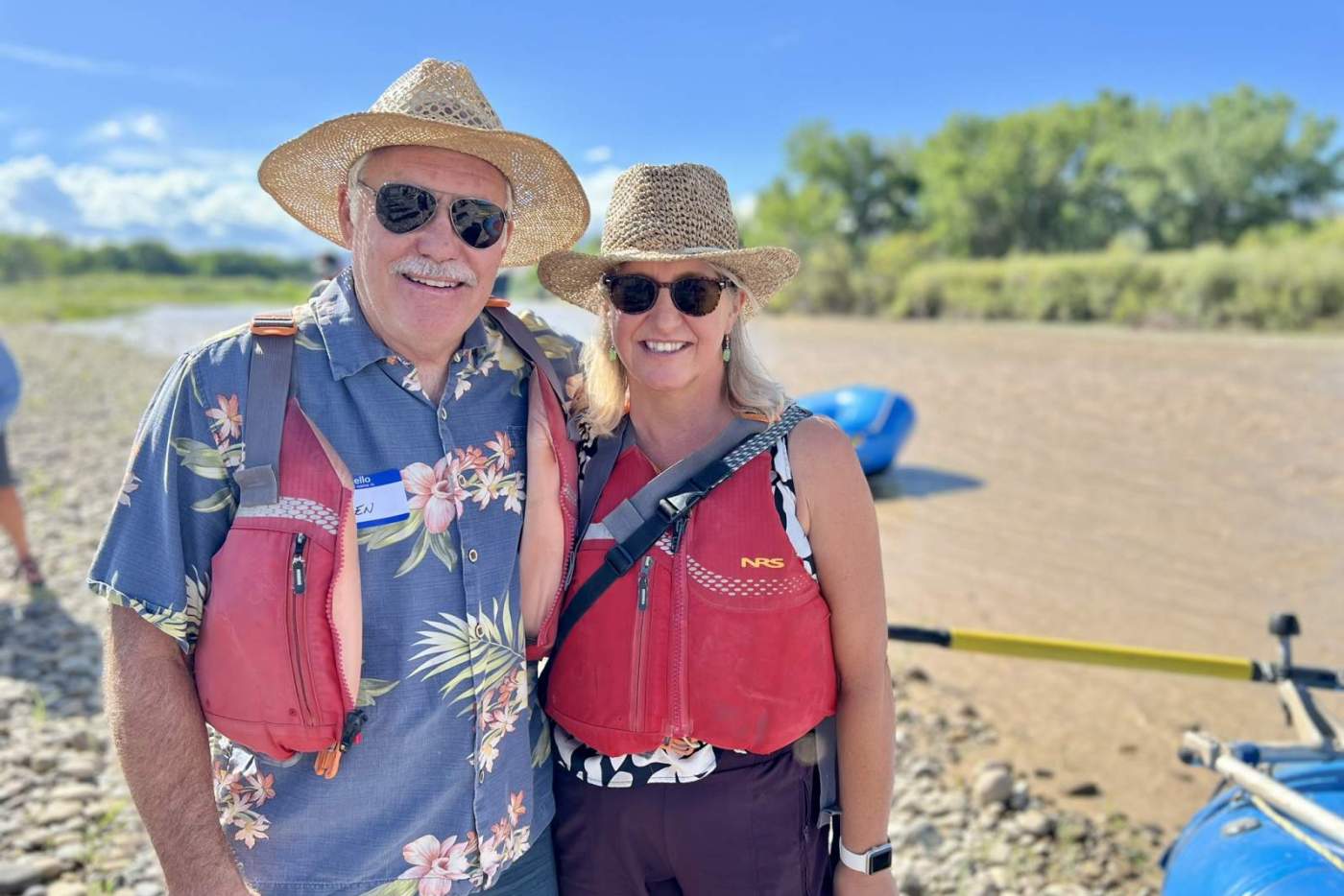 Man and woman in hats and life vests on the riverside