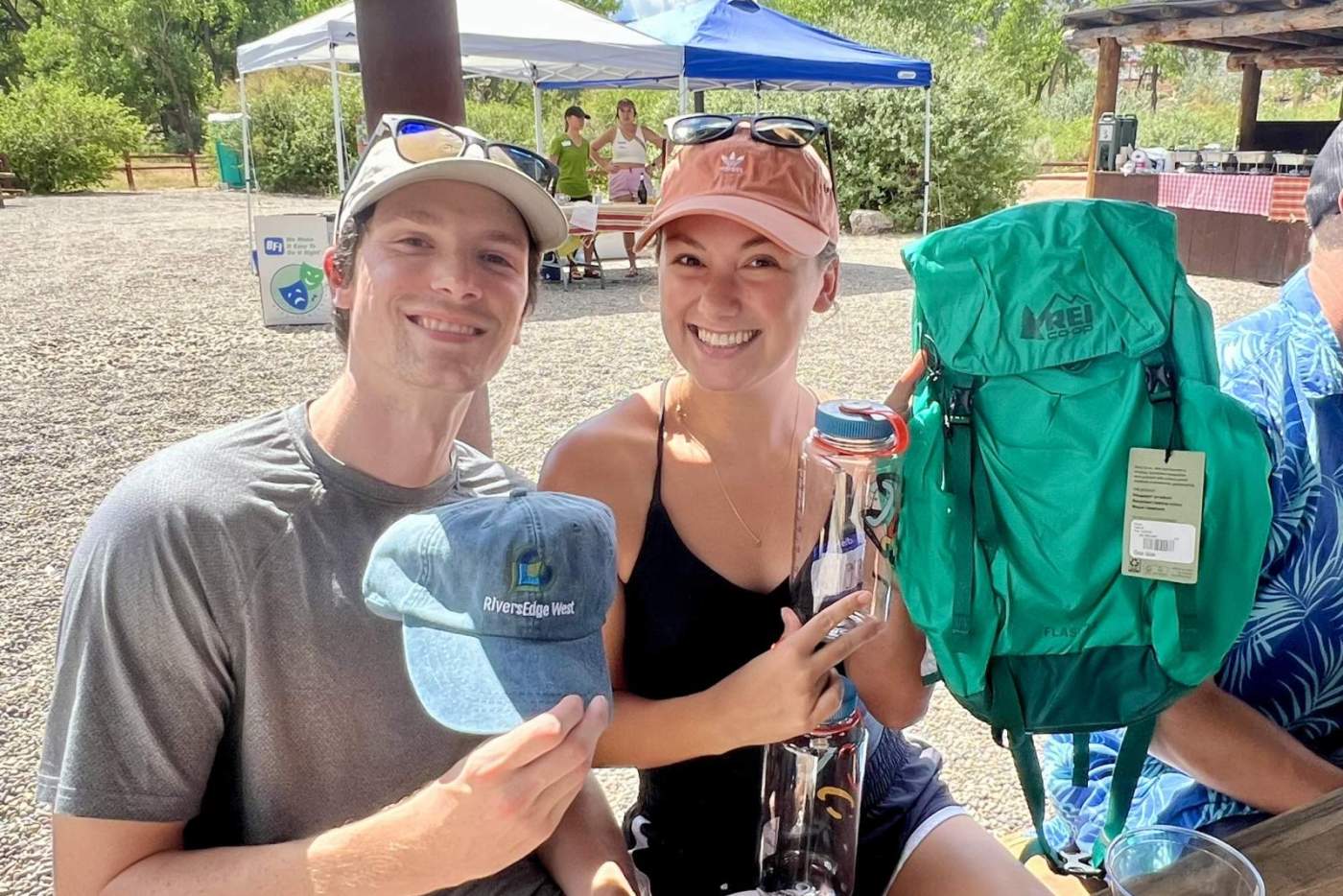 young man holds a blue cap and young woman holds a teal backpack