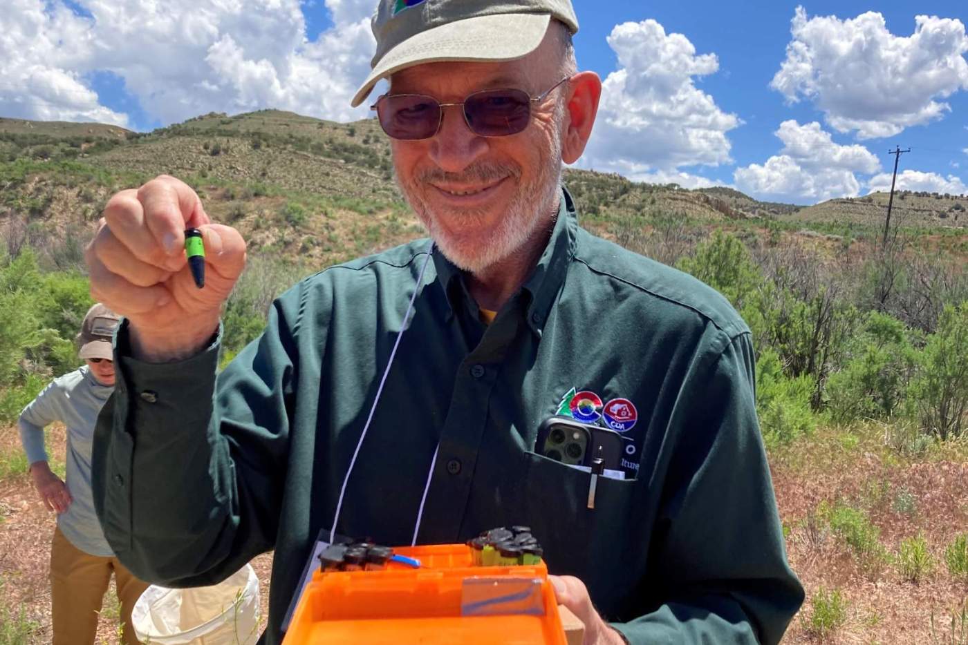 man holds up test tube outside